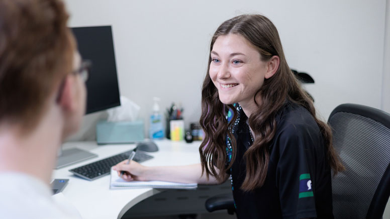 a women taking note and she's happy while doing it